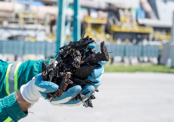 Close up of man holding shredded tires in front of rotary cement kiln used as alternative fuel © Drpixel