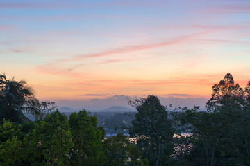 Sunrise colorful sky with clouds and foggy hills on horizon in the early morning in tropical country