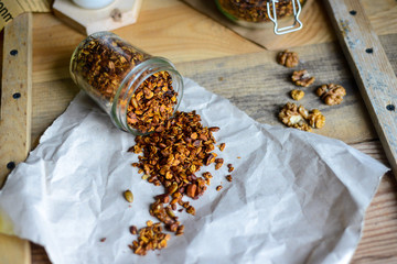 tasty homemade oats granola with nuts and berries in glass jar served with coconut milk on the wood table for breakfast early in the morning
