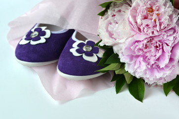 Suede leather ballerina flats shoes wrapped in gift tissue paper  with pink peonies bouquet and copy space