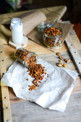tasty homemade oats granola with nuts and berries in glass jar served with coconut milk on the wood table for breakfast early in the morning