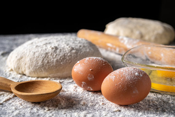 White flour with eggs, butter and dough on a cooking board