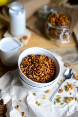tasty homemade oats granola with nuts and berries in white ceramic bowl served with coconut milk on the wood table for breakfast early in the morning