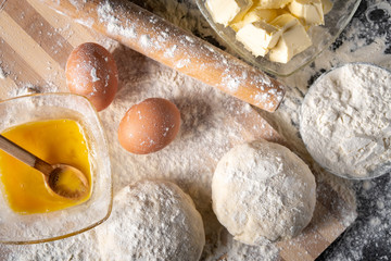 White flour with eggs, butter and dough on a cooking board