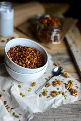 tasty homemade oats granola with nuts and berries in white ceramic bowl served with coconut milk on the wood table for breakfast early in the morning