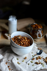 tasty homemade oats granola with nuts and berries in white ceramic bowl served with coconut milk on the wood table for breakfast early in the morning