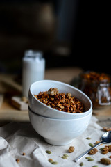 tasty homemade oats granola with nuts and berries in white ceramic bowl served with coconut milk on the wood table for breakfast early in the morning