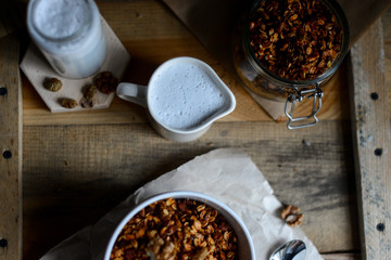 tasty homemade oats granola with nuts and berries in white ceramic bowl served with coconut milk on the wood table for breakfast early in the morning