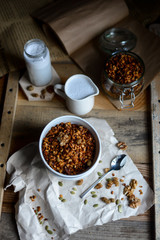 tasty homemade oats granola with nuts and berries in white ceramic bowl served with coconut milk on the wood table for breakfast early in the morning