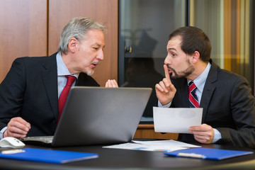 Businessman asking his colleague to speak silently