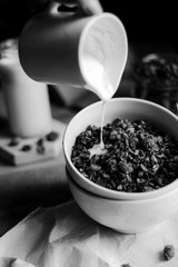 tasty homemade oats granola with nuts and berries in white ceramic bowl served with coconut milk on the wood table for breakfast early in the morning