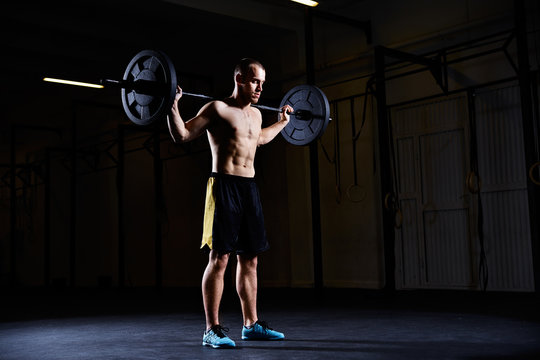 Athletic man exercising with barbell at gym