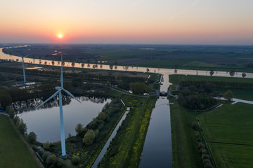 Obraz premium Wind turbines generating green energy during sunset as seen from above in Waalwijk, Noord Brabant, Netherlands