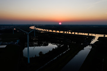 Fototapeta premium Wind turbines generating green energy during sunset as seen from above in Waalwijk, Noord Brabant, Netherlands
