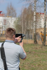 A young man videotaping on a smartphone. Uses gimbal to get smooth shots. Controls the recording by touching the screen.