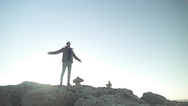 Man stands on a desert cliff with arms open wide