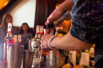 barman preparing cocktail in a cocktail bar andr pours liquid into the jigger.