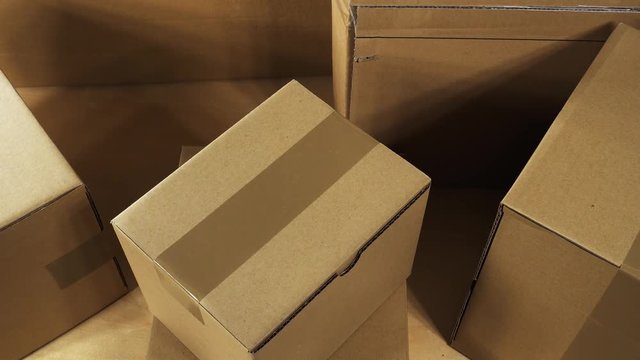 Pan over brown carton box parcels stacked on wooden office desk ready for shipment or just delivered