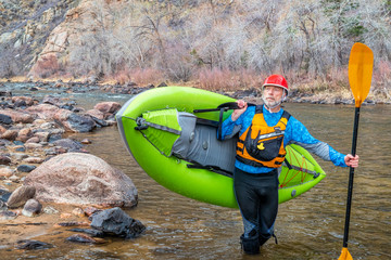 senior paddler carrying  inflatable whitewater kayak