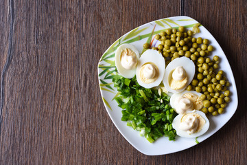 Boiled eggs under mayonnaise with green peas and green onions. A traditional russian dish.