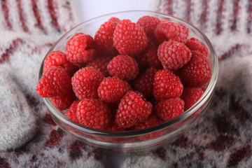 raspberries in a glass bowl on a knitted woolen background. winter concept