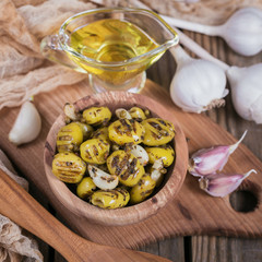 Grilled olives with garlic, olive oil and spices on wooden background
