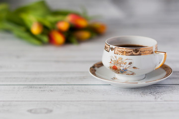 Cup of coffee and colorful tulips on wooden background