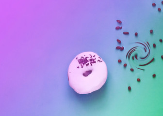 White glazed donut  with black chocolate sweets on purple background.  Colorful breakfast. 