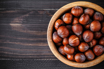 Filtered image of Hazelnuts in a wooden bowl on rustic background,top view.