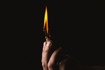 Burning match in the man's hand. Dangerous game with fire.