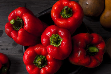 FRESH RED PEPPERS IN THE FOREGROUND IN BLACK CLAY BOWL