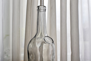 The upper part of the glass bottle against the window