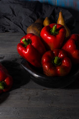 FRESH RED PEPPERS IN THE FOREGROUND IN BLACK CLAY BOWL