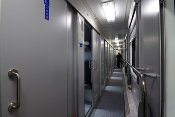 Corridor with doors and people standing at the end of a First Class sleeping carriage of a passenger train