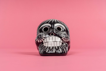 calavera negra sobre fondo rosa, artesania de barro mexicana