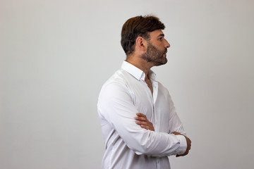 Fashion portrait of handsome young man with brown hair showing confidence, facing forwards and looking at the side. Isolated on white background.