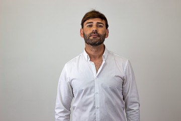 Fashion portrait of handsome young man with brown hair showing confidence, looking at the camera. Isolated on white background.
