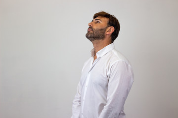 Obraz premium Fashion portrait of handsome young man with brown hair and a look of disgust, facing forwards and looking at the horizon. Isolated on white background.