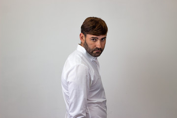 Obraz premium Fashion portrait of handsome young man with brown hair and a look of disgust, their back facing the camera and looking at the camera. Isolated on white background.