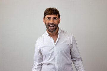 Fashion portrait of handsome young man with brown hair looking happy, looking at the camera. Isolated on white background.