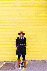 young beautiful woman having fun with her dog. Yellow brick wall background. Love and pets outdoors. City and urban.