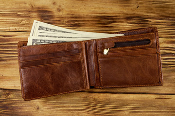 Opened wallet with american dollars on wooden table. Top view