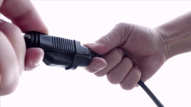 Man's hands plug in and unplug end of extension cord