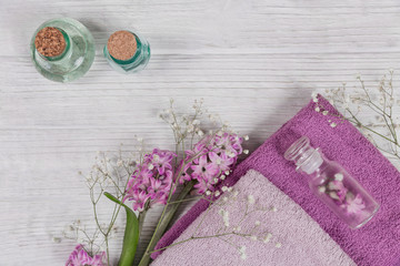Abstract composition of purple hyacinths flowers, towels and bottles of organic cosmetic with essential oil