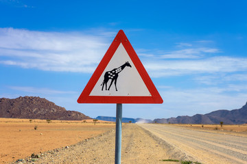 Giraffes crossing warning road sign placed in the desert of Namibia