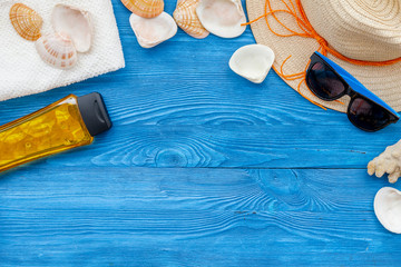 Summer travaling to the sea with straw hat, sun glasses, sunblock lotion on blue wooden background top view mock up