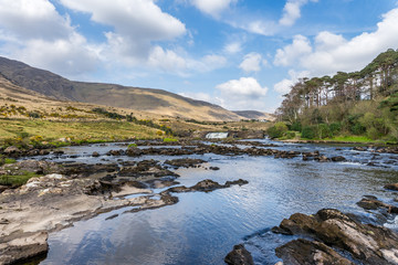Fototapeta na wymiar paysage de rivière avec sa cascade et les collines pelées du Connemara