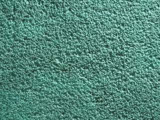 Coarse plaster painted green with a porous texture background