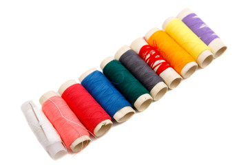 Many colorful thread spools on white background