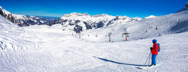 Beautiful winter landscape with Swiss Alps. Skiers skiing in famous Engelgerg - Titlis ski resort,...